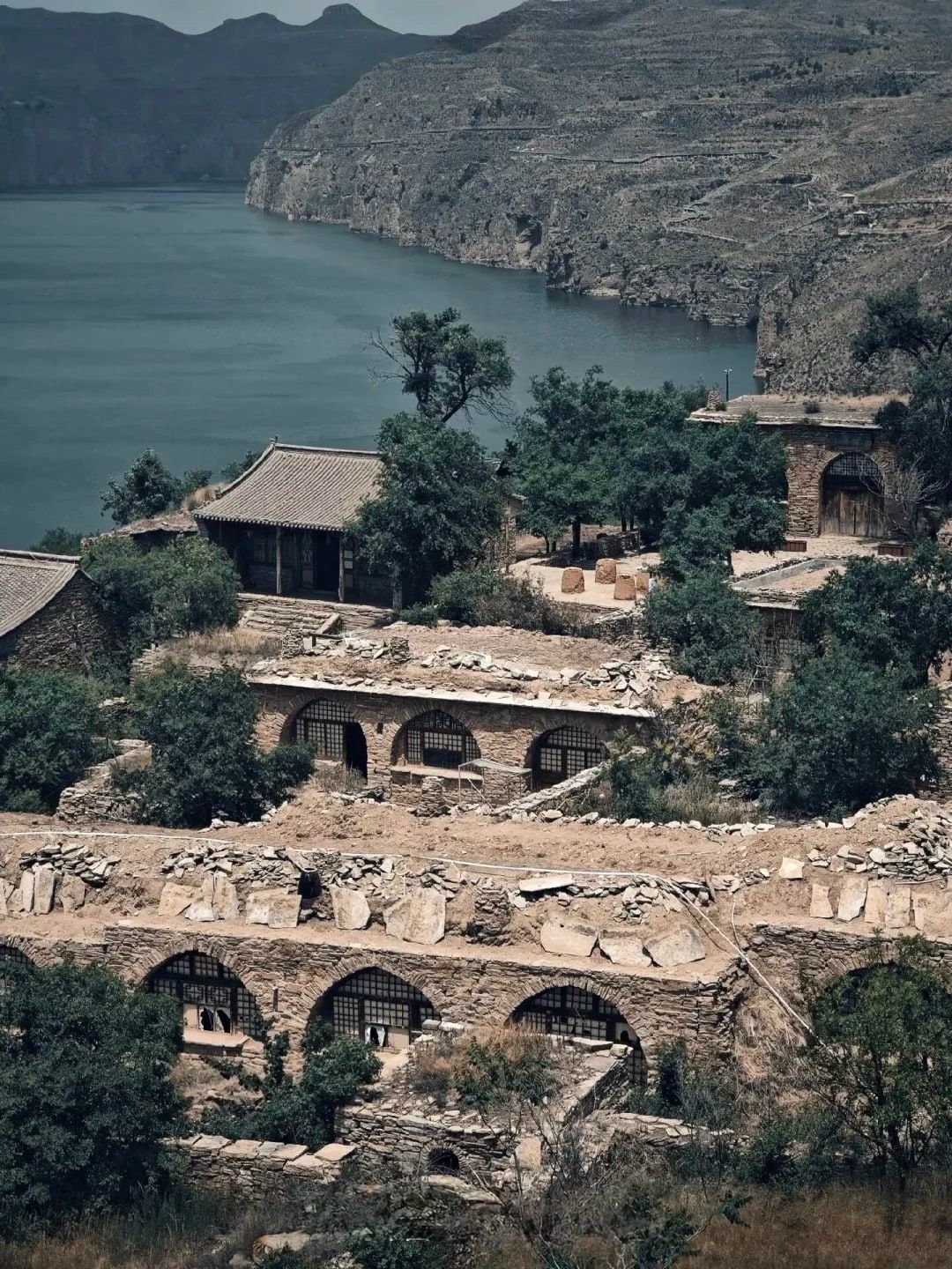 Stone-arched cave houses stepping down the hillside, the Yellow River and its cliffs behind