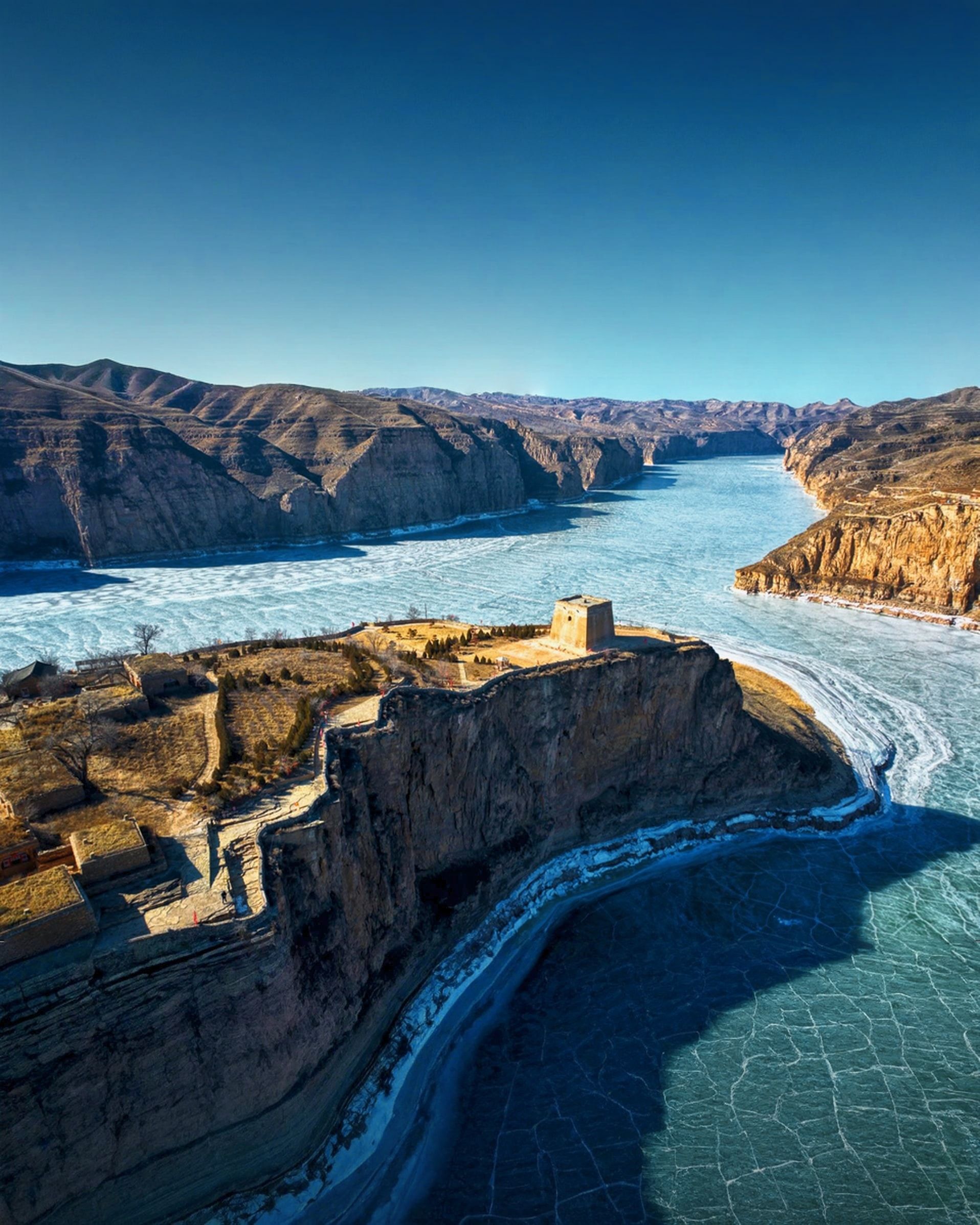 A Ming watchtower on the cliff edge where the frozen Yellow River bends around Laoniuwan