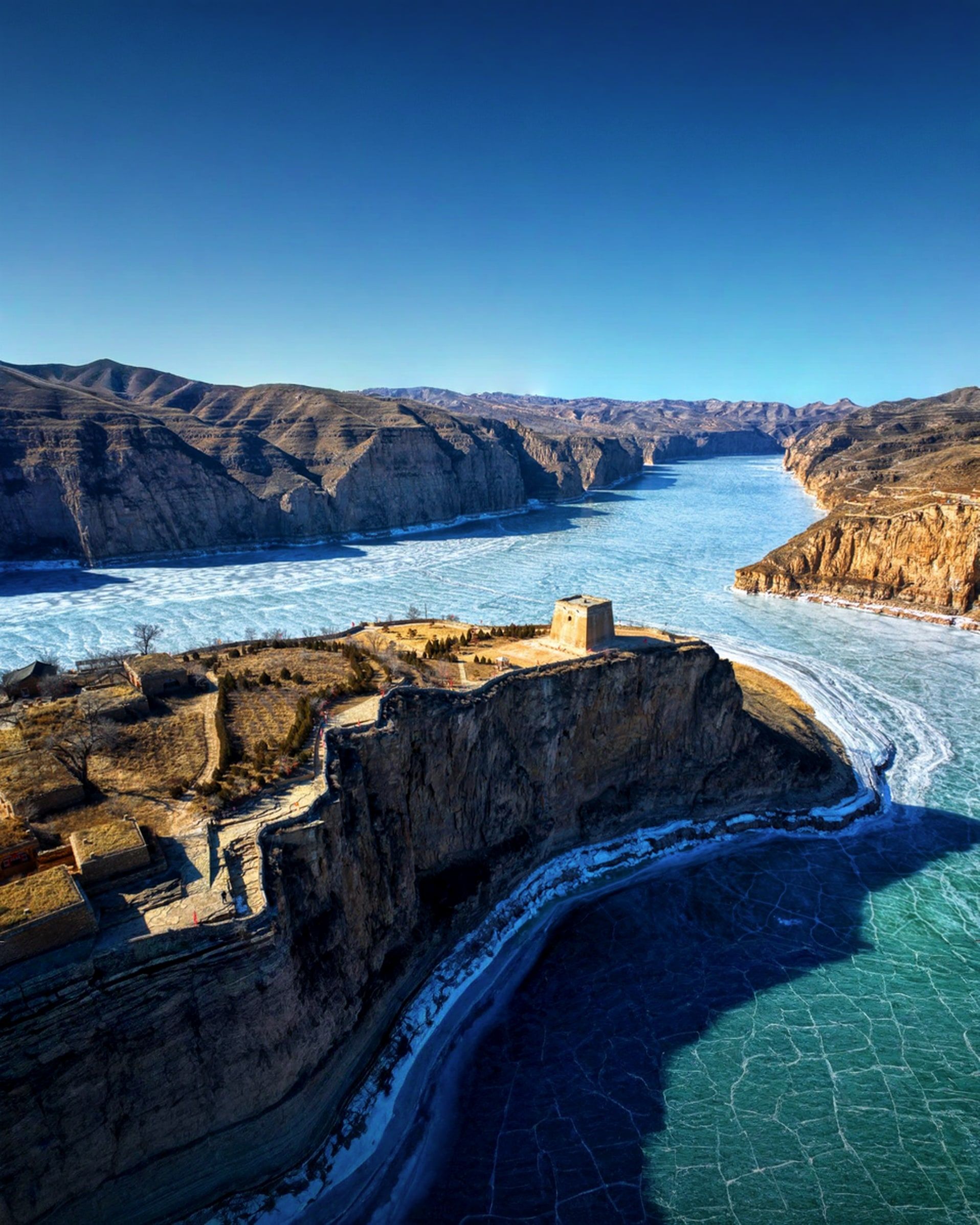 Ein Ming-Wachturm an der Felskante, wo sich der gefrorene Gelbe Fluss um Laoniuwan biegt