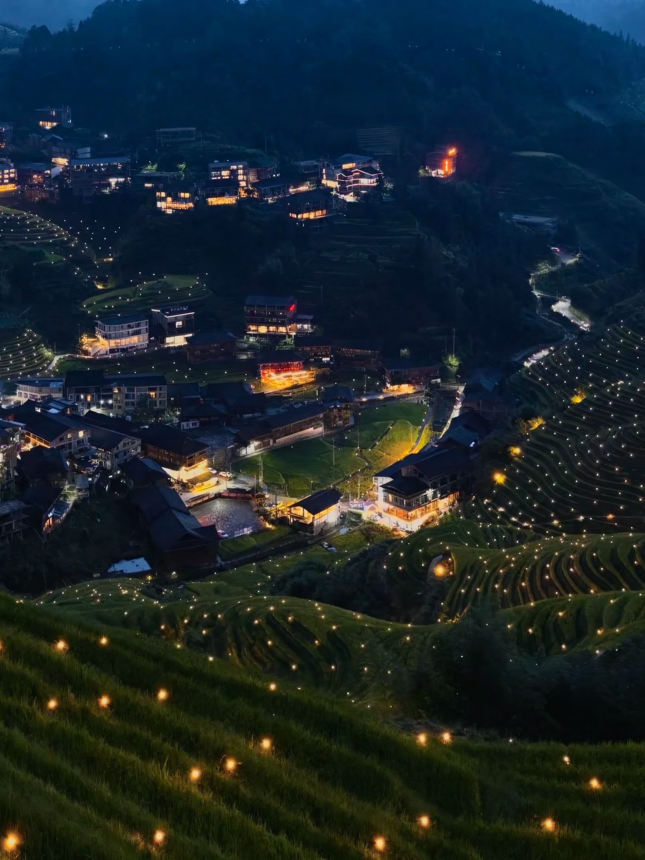 Abenddämmerung über einem Dorf in den Terrassen, kleine Lichter entlang der Feldränder
