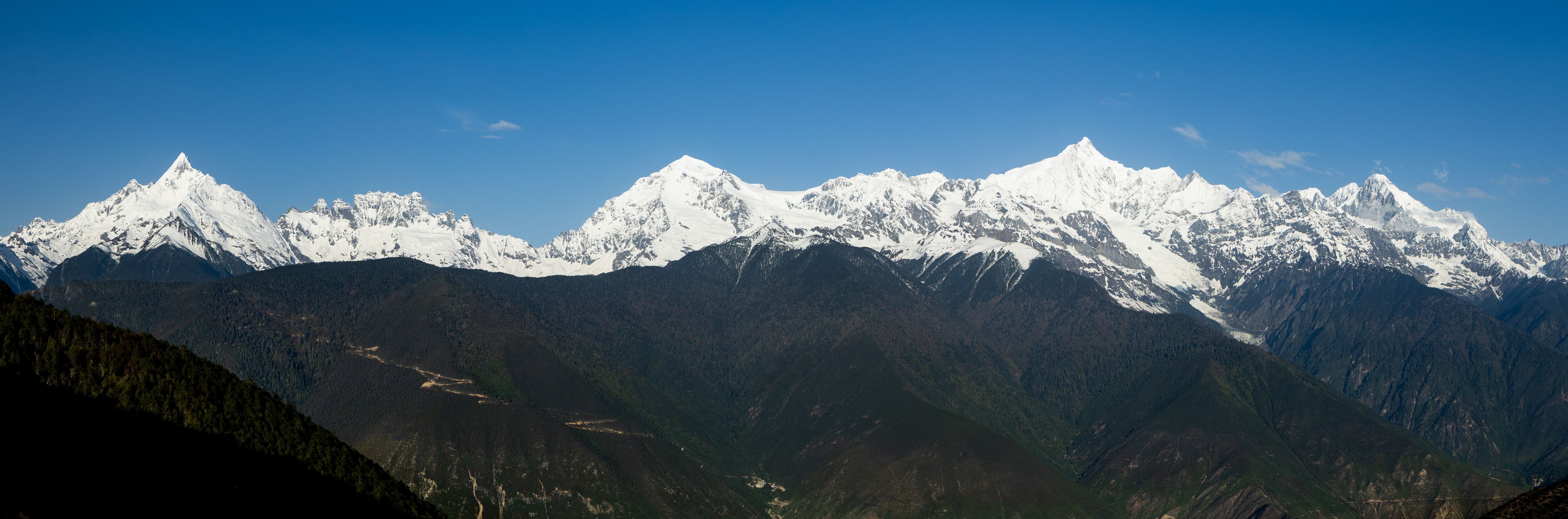 The whole Meili range in morning sun, from Miancimu on the left to Kawagebo, above dark forested ridges