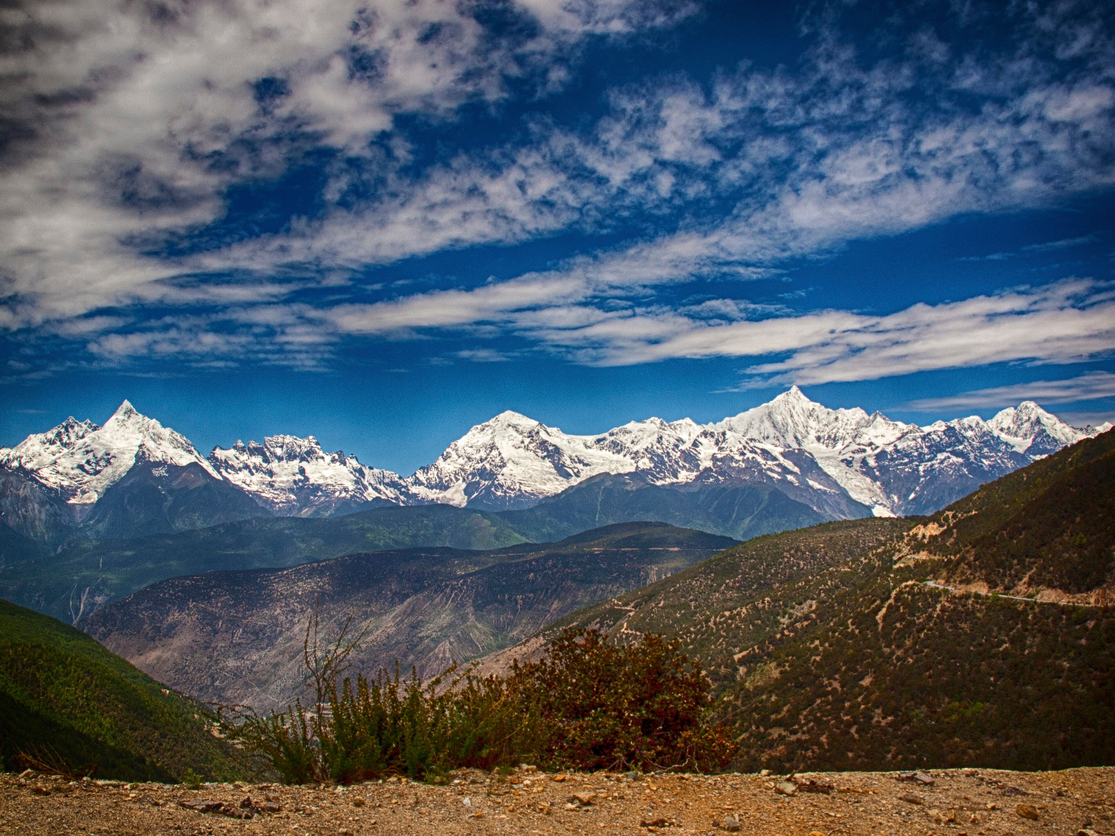 The whole Meili snow range under a blue sky with streaks of cloud