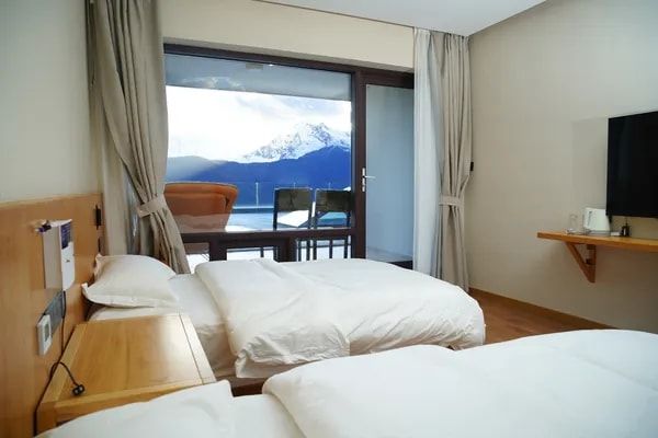 A twin room at Snow Mountain Wake Up Hotel, its balcony facing a snow peak