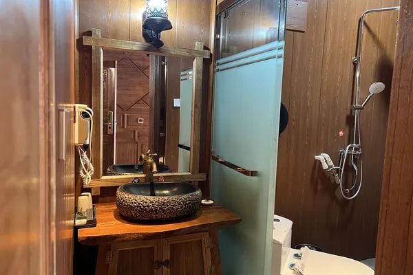 A ZHIYU bathroom: a stone basin on a wooden counter and a shower behind a glass door