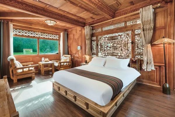 A wood-panelled room at ZHIYU in Lower Yubeng: a big bed, carved lattice and a window onto the forest