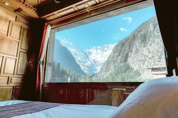 Snow peaks above Yubeng through the wide window of a ZHIYU room, seen from the bed