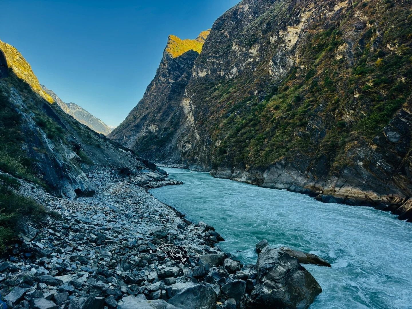 Les rapides turquoise du Jinsha le long d’une rive de blocs gris, le haut des parois de la gorge doré par le soleil