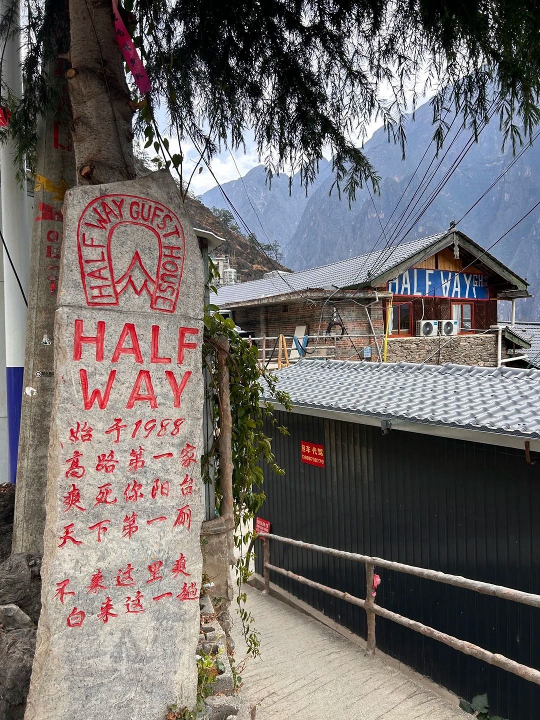 La pierre peinte HALF WAY devant la Halfway Guesthouse, avec la maison et les montagnes derrière