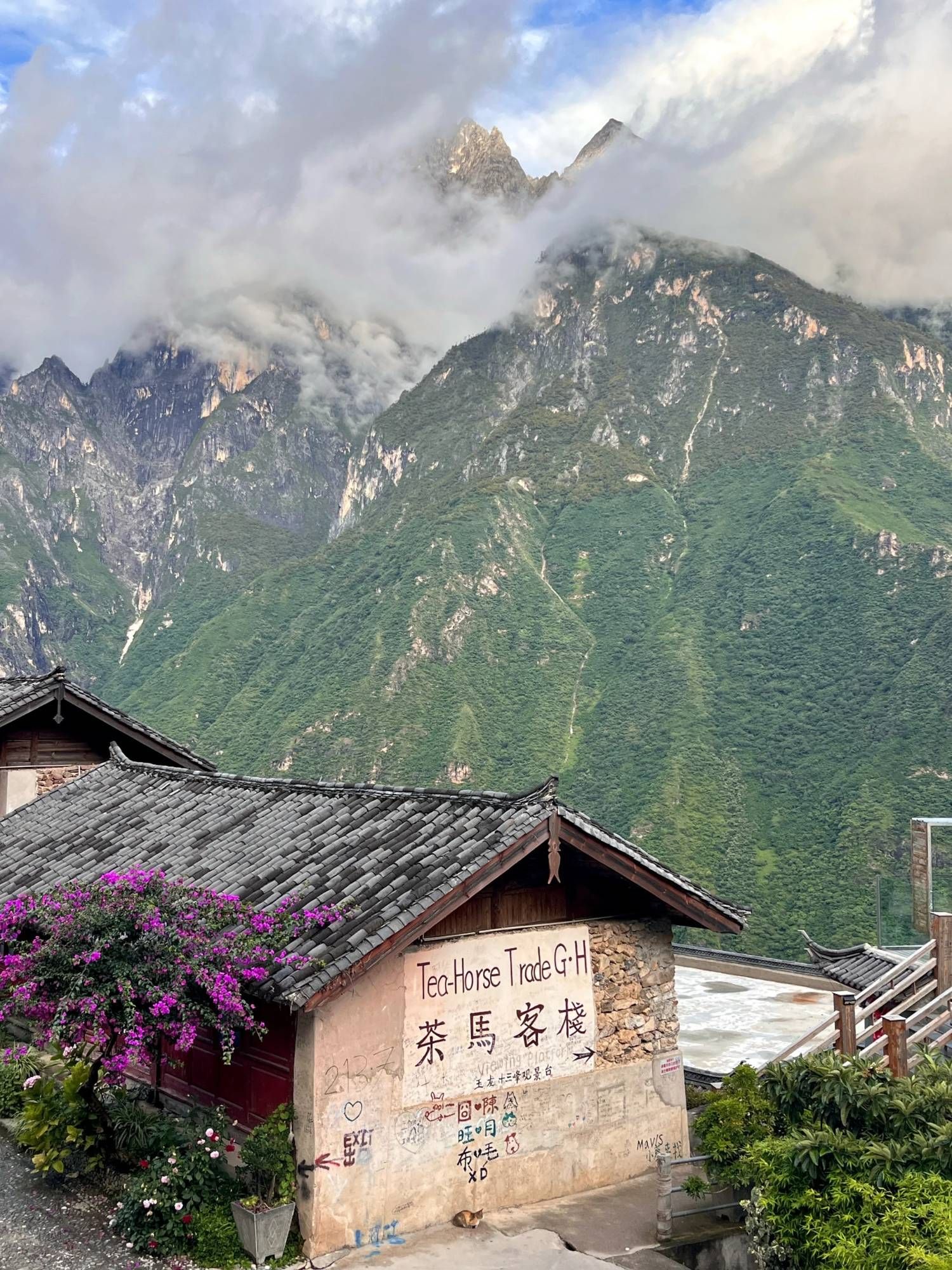 La Tea Horse Guesthouse, son enseigne peinte et ses bougainvilliers, des nuages sur les sommets de l’autre côté de la gorge