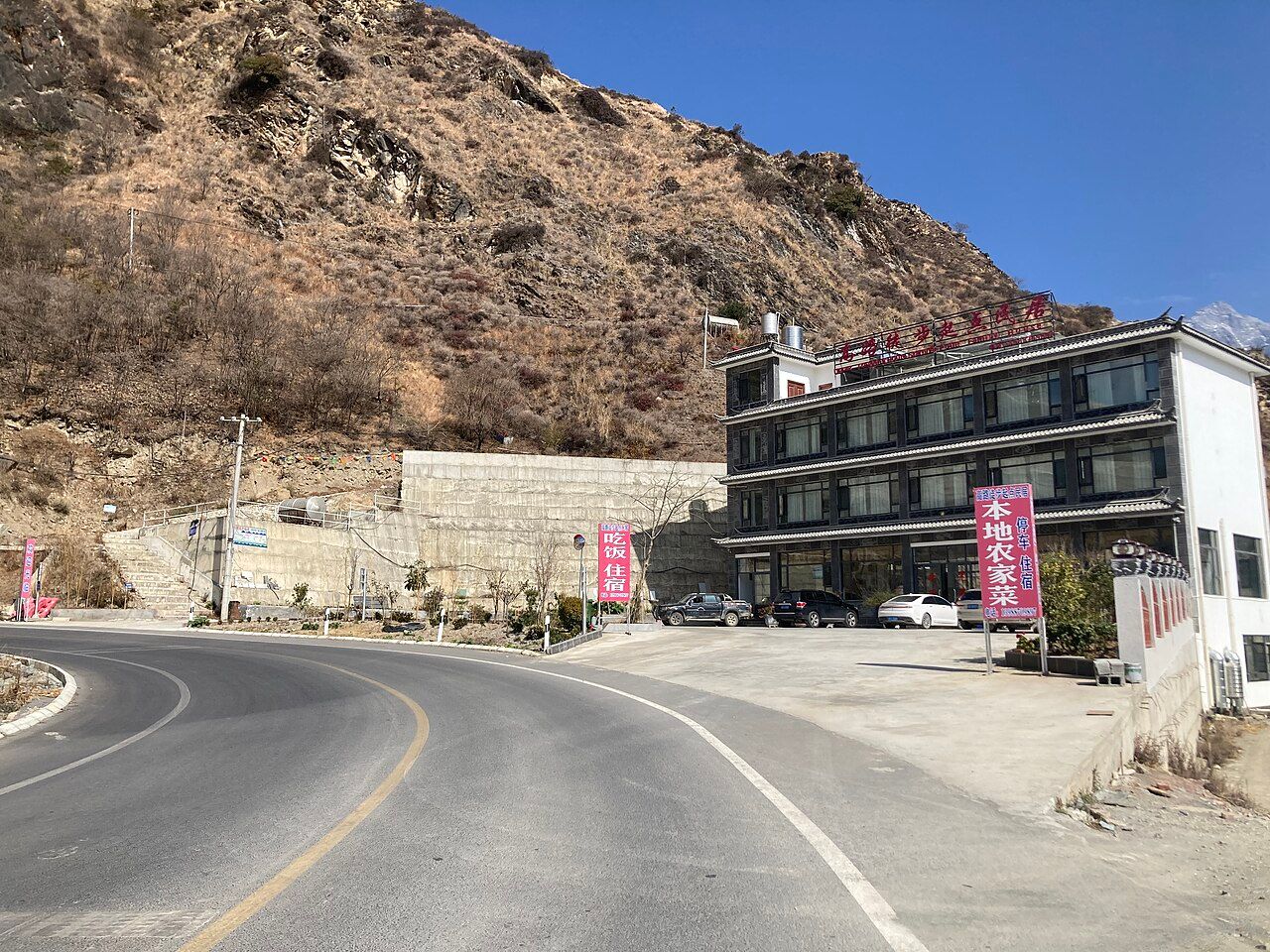 The start of the Tiger Leaping Gorge High Trail at Qiaotou: the road and a new guesthouse below a dry hillside