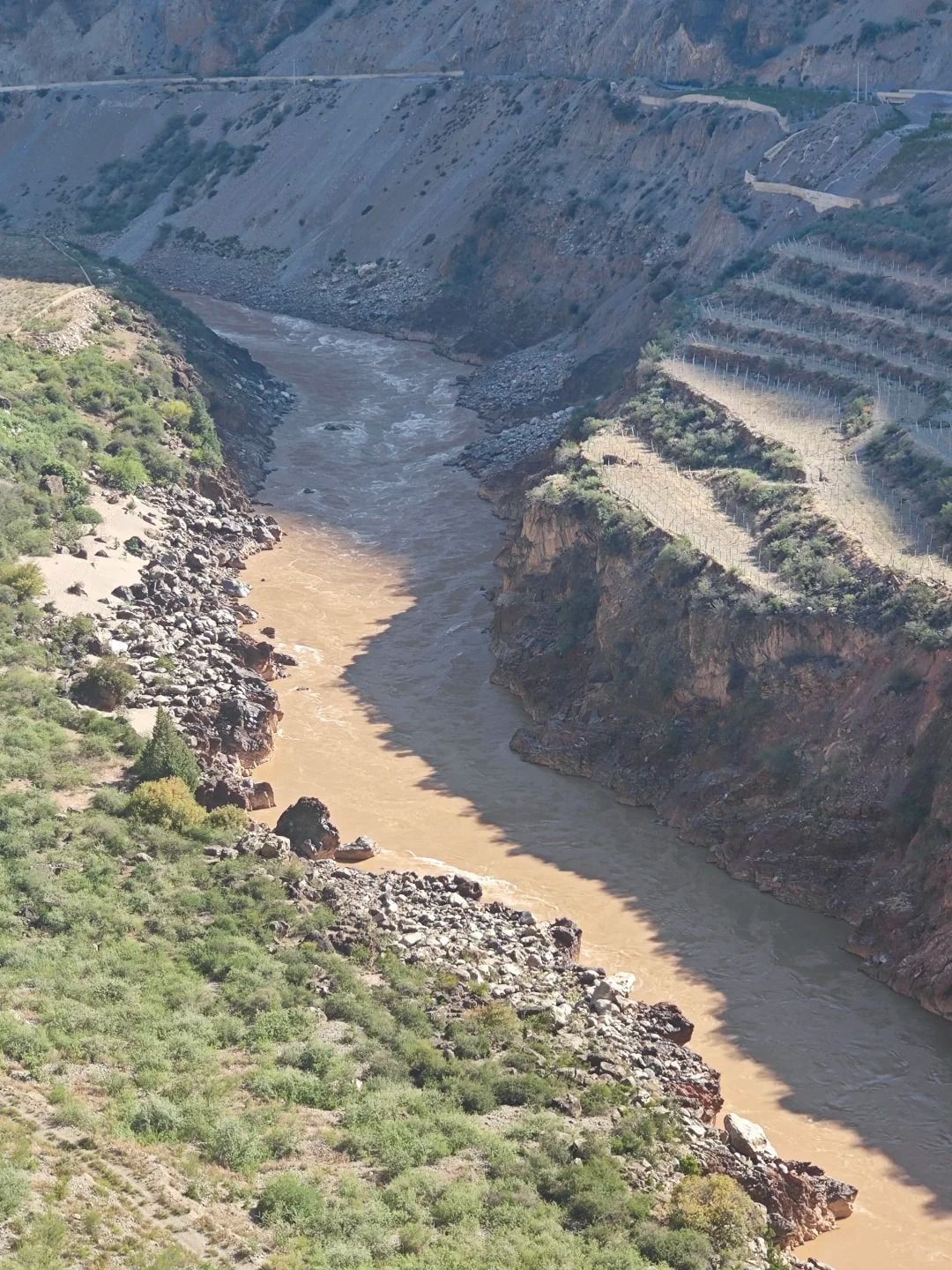 Der schlammig braune Mekong windet sich unten durch eine trockene Schlucht, am anderen Ufer Terrassenfelder